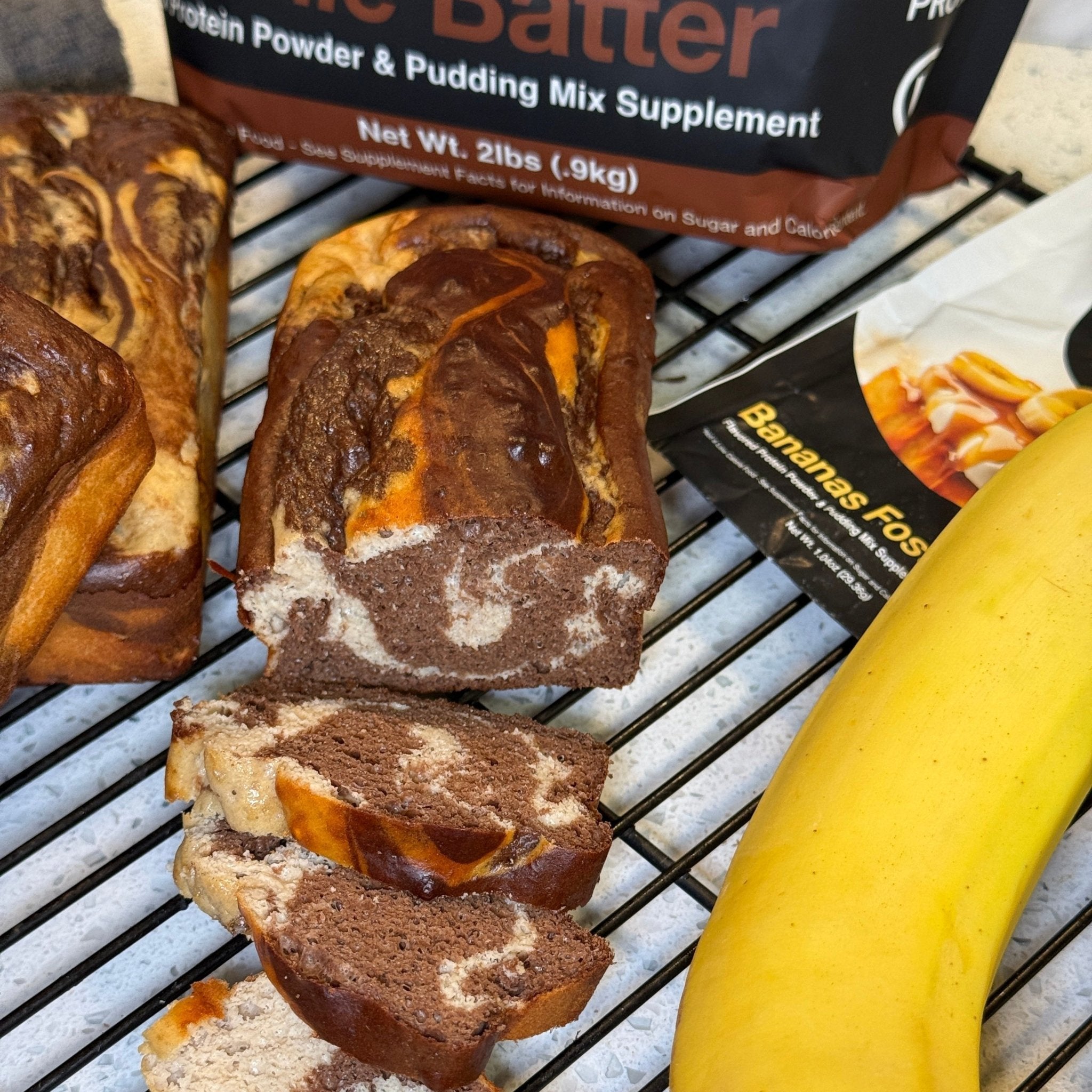 Chocolate banana bread swirl mini loaves made with Devotion Nutrition Brownie Batter protein powder and Bananas Foster protein powder, sliced beside fresh banana.
