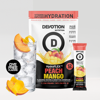 A Devotion Nutrition HydroFlex Peach Mango flavored water and smoothie enhancer pack shown with a large 12-count bag a single stick packet and a glass of iced water garnished with peach slices on a light gray background.