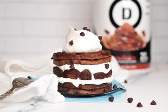 Devotion Nutrition Brownie Batter protein powder package with a milkshake and brownies on a light gray background