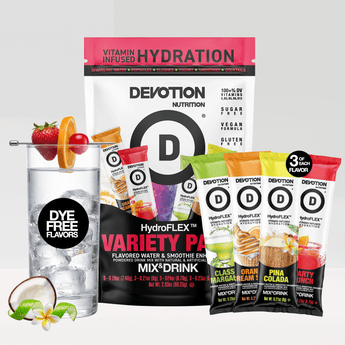 A Devotion Nutrition HydroFlex Variety Pack mix drink pouch and single-serve packets displayed with a glass of water and fruit garnish on a light gray background.