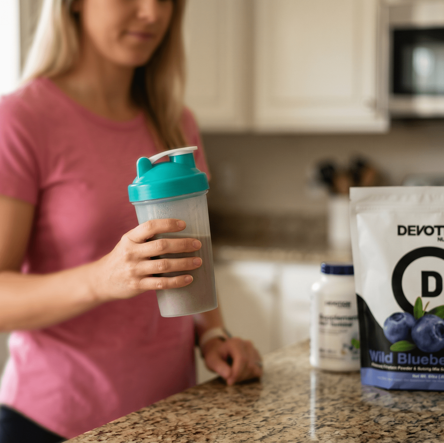 Women in her kitchen with bag of Blueberry proteinpowder and a shaker cup