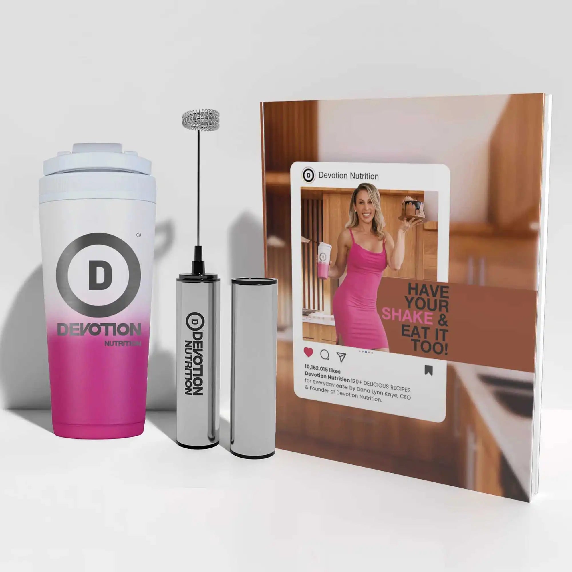 Pink and white tumbler with a milk frother and a cookbook featuring Devotion Nutrition on a white background