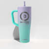 A tall insulated tumbler with a handle and straw, shown on a clean white studio background. The tumbler has a lavender-to-turquoise gradient finish and features the Devotion Nutrition logo and name on the front, with the Icesmoker brand name near the bottom.
