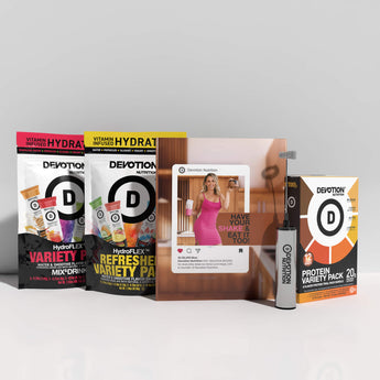 Collection of Devotion Nutrition products including protein packs and a magazine on a white surface.