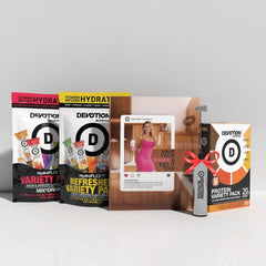 Collection of Devotion Nutrition products including protein packs and a magazine on a white surface.